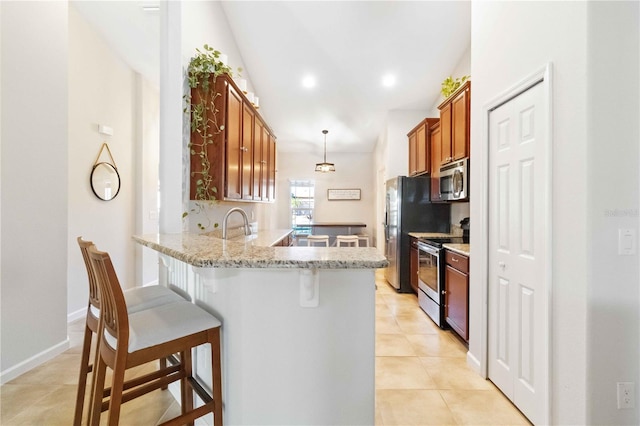 kitchen with appliances with stainless steel finishes, light stone counters, light tile patterned flooring, decorative light fixtures, and kitchen peninsula