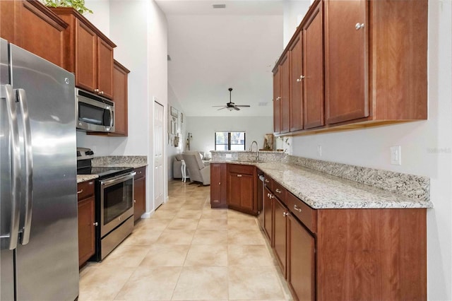 kitchen featuring sink, ceiling fan, appliances with stainless steel finishes, light stone counters, and kitchen peninsula