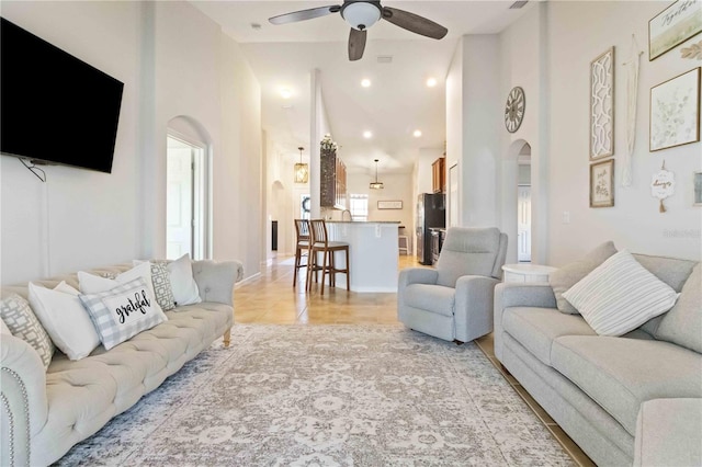 living room featuring ceiling fan, a high ceiling, and light tile patterned floors