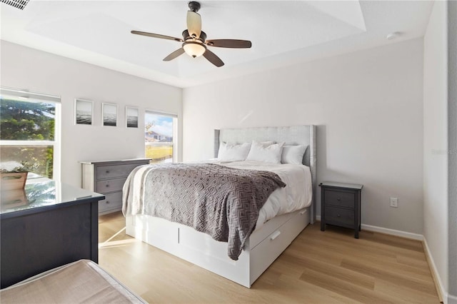 bedroom featuring a tray ceiling, light hardwood / wood-style flooring, and ceiling fan