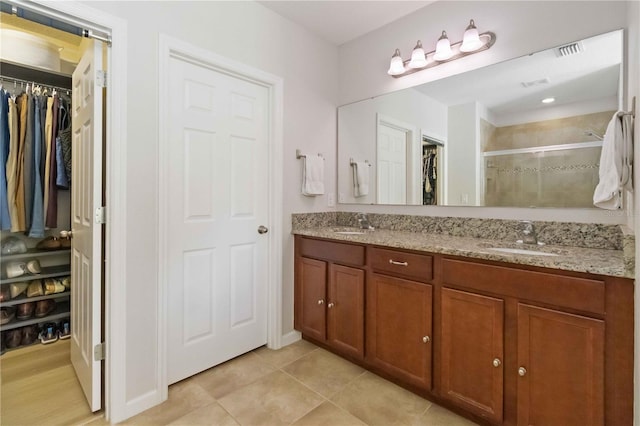 bathroom featuring tile patterned floors, vanity, and a shower with shower door