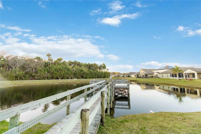 view of dock featuring a lawn and a water view