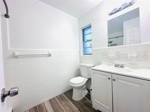 bathroom with wood-type flooring, toilet, and vanity