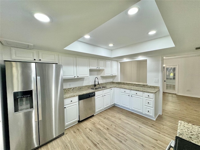 kitchen featuring sink, stainless steel appliances, light hardwood / wood-style floors, white cabinets, and a raised ceiling