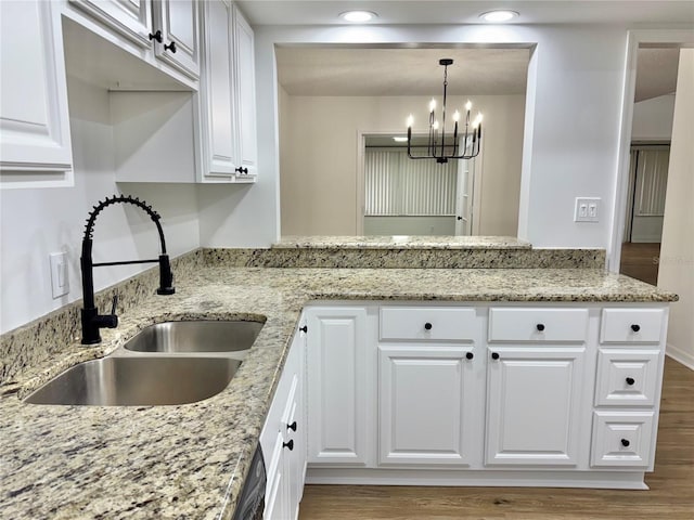 kitchen with hanging light fixtures, white cabinetry, and sink