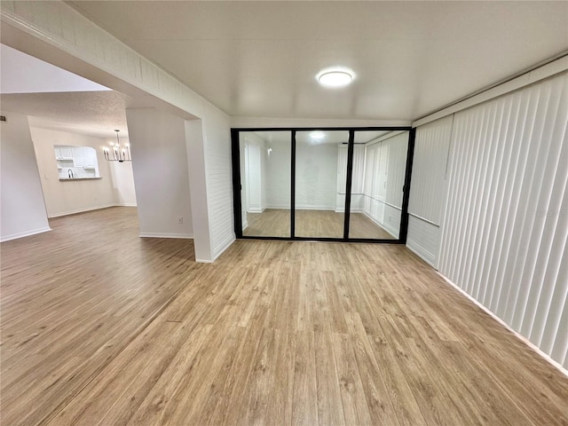 unfurnished room with a notable chandelier and light hardwood / wood-style flooring