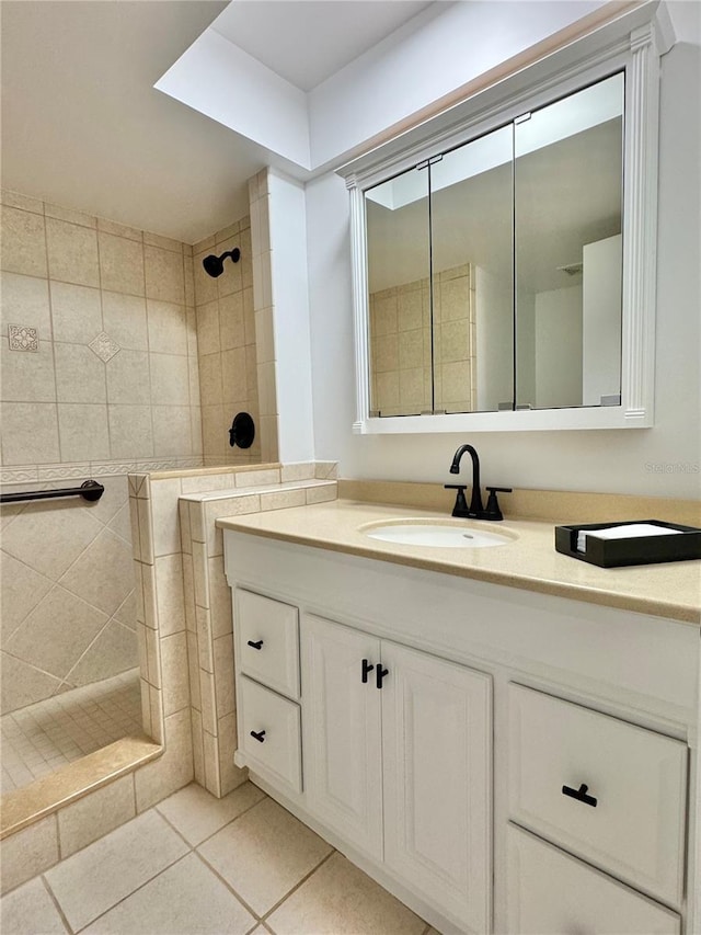 bathroom with tile patterned flooring, vanity, and tiled shower