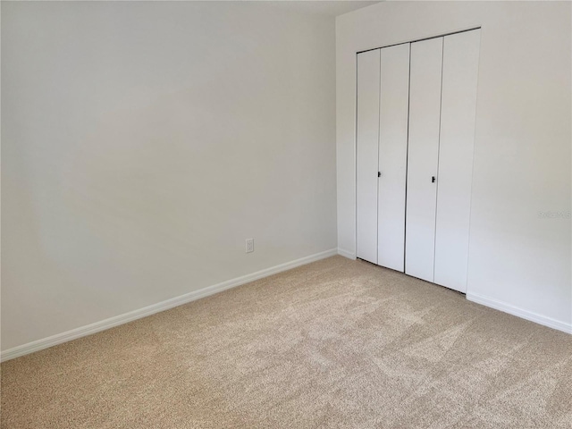 unfurnished bedroom with light colored carpet and a closet