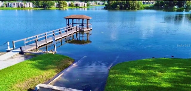 view of dock with a water view and a yard