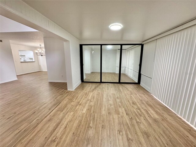 spare room with a notable chandelier and light hardwood / wood-style floors