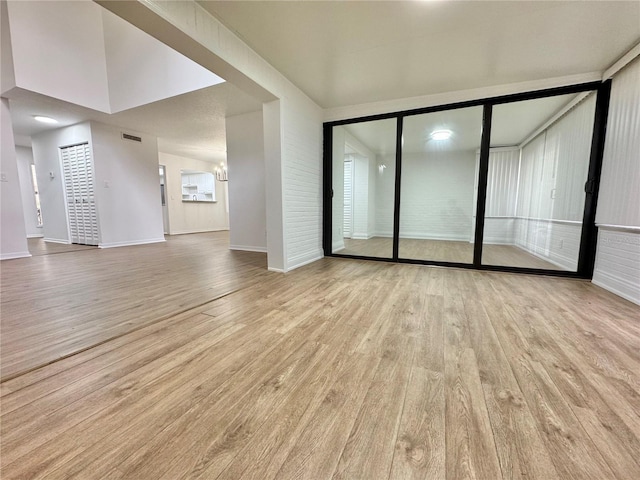 unfurnished living room with a notable chandelier and light hardwood / wood-style floors