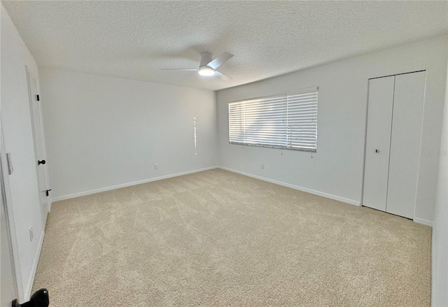 unfurnished bedroom featuring ceiling fan, light colored carpet, and a textured ceiling