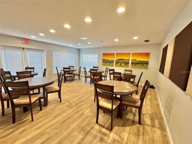 dining area with light hardwood / wood-style floors and a textured ceiling