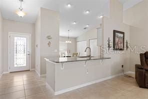 kitchen featuring sink, a breakfast bar, hanging light fixtures, light tile patterned flooring, and kitchen peninsula