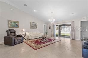 tiled living room featuring an inviting chandelier and vaulted ceiling