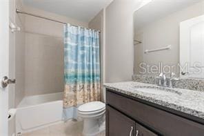 full bathroom with shower / tub combo with curtain, vanity, and toilet