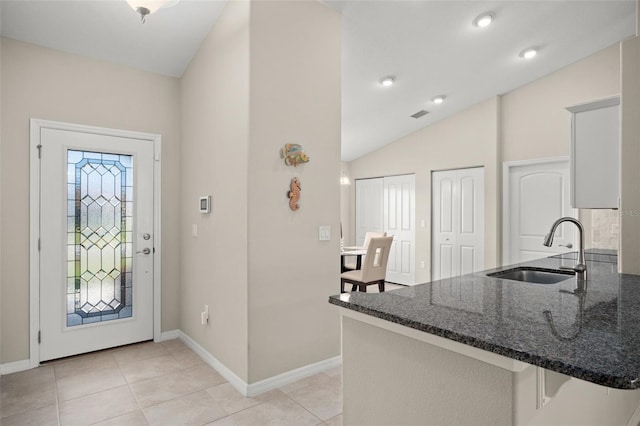 foyer with baseboards, vaulted ceiling, and light tile patterned flooring