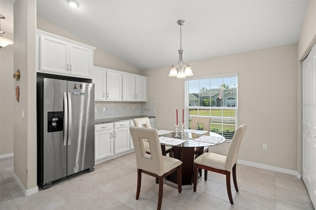 dining area featuring a chandelier, vaulted ceiling, baseboards, and light tile patterned floors