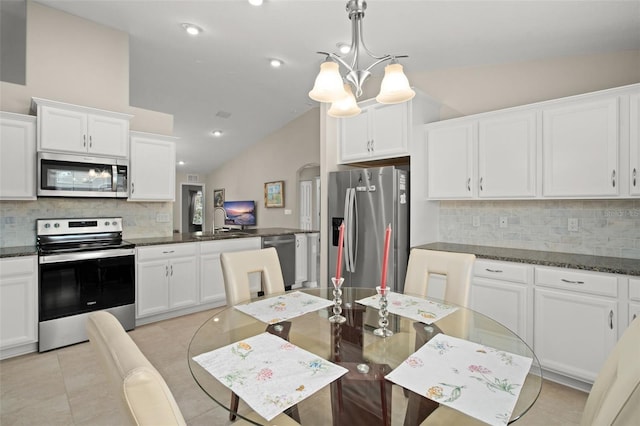 kitchen with arched walkways, light tile patterned floors, lofted ceiling, appliances with stainless steel finishes, and white cabinets