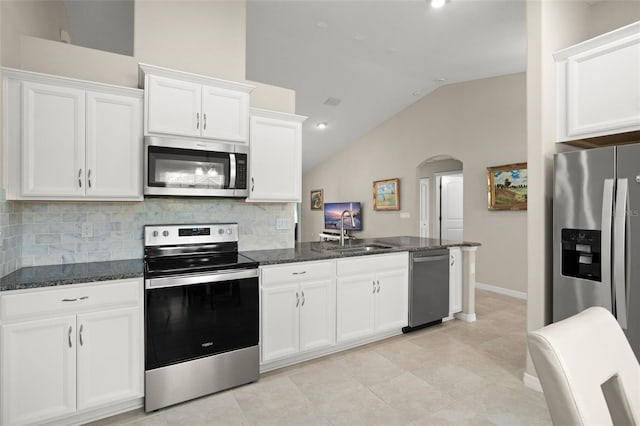 kitchen featuring tasteful backsplash, arched walkways, appliances with stainless steel finishes, white cabinetry, and a sink