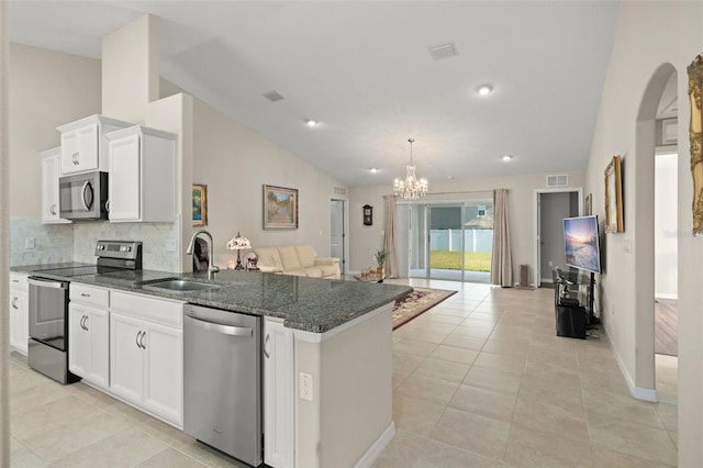 kitchen with stainless steel appliances, visible vents, open floor plan, a sink, and vaulted ceiling