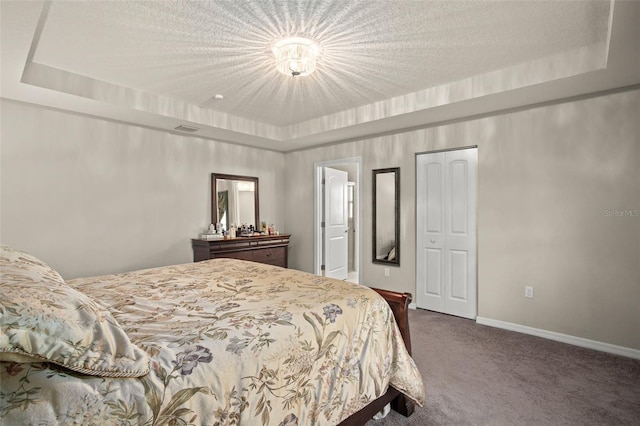 bedroom with baseboards, dark carpet, a raised ceiling, and a textured ceiling