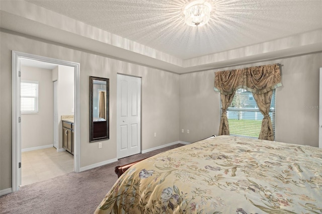 carpeted bedroom featuring a textured ceiling, connected bathroom, and baseboards