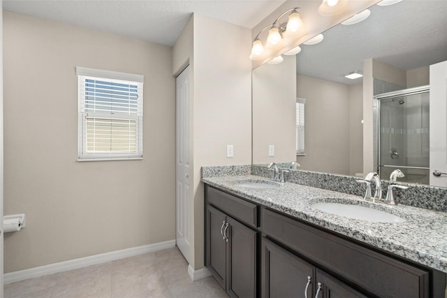 bathroom featuring a stall shower, a sink, baseboards, and double vanity