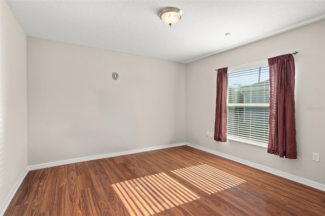 empty room with baseboards and wood finished floors