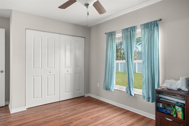 bedroom with ceiling fan, a closet, wood finished floors, and baseboards