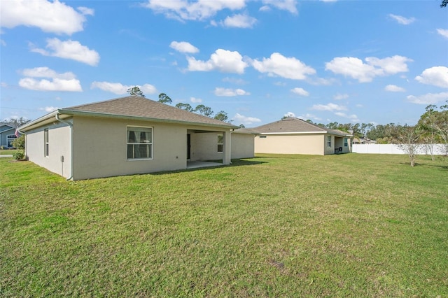 rear view of property with stucco siding, fence, a patio, and a yard