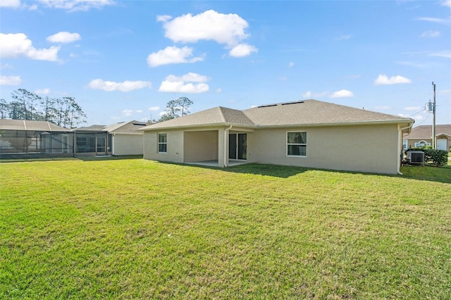 rear view of property with central air condition unit, a lawn, and stucco siding