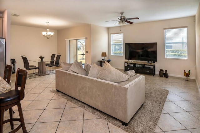 tiled living room featuring ceiling fan with notable chandelier