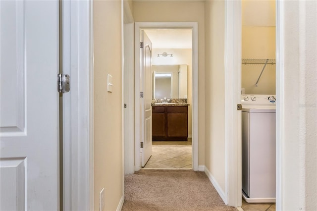 hallway featuring light carpet and washer / dryer