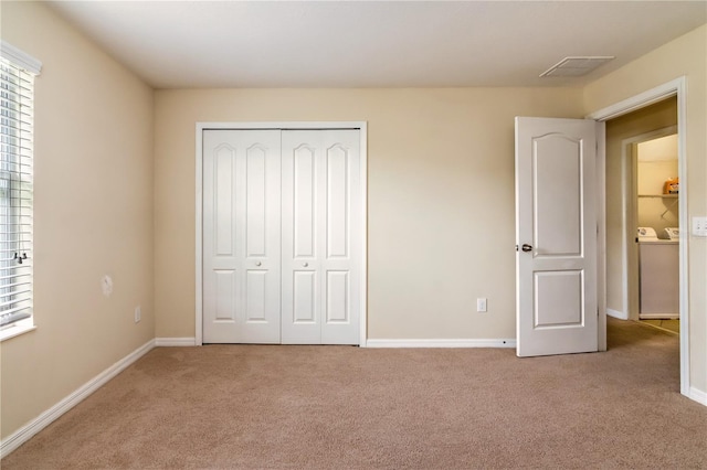 unfurnished bedroom with light carpet, washer / clothes dryer, and a closet