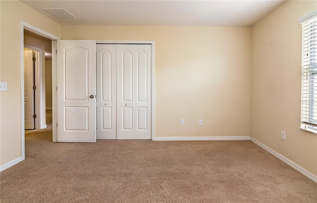 unfurnished bedroom featuring multiple windows, light colored carpet, and a closet