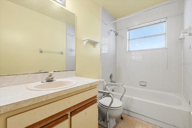 full bathroom featuring tiled shower / bath combo, vanity, and toilet