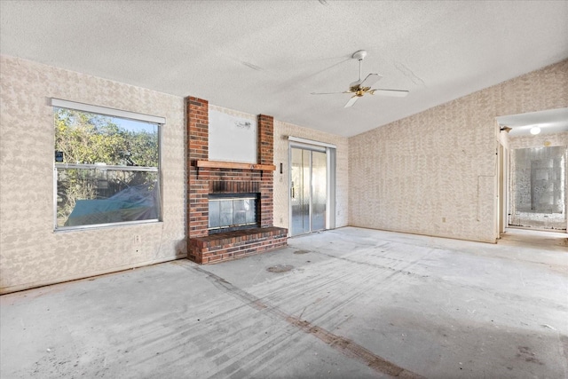 unfurnished living room with ceiling fan, a textured ceiling, and a fireplace