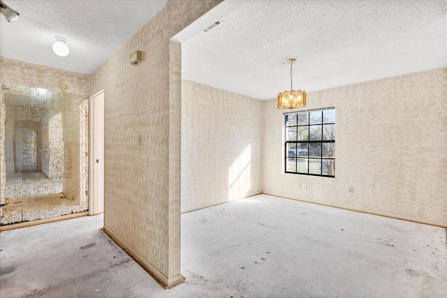 spare room with a chandelier and concrete floors