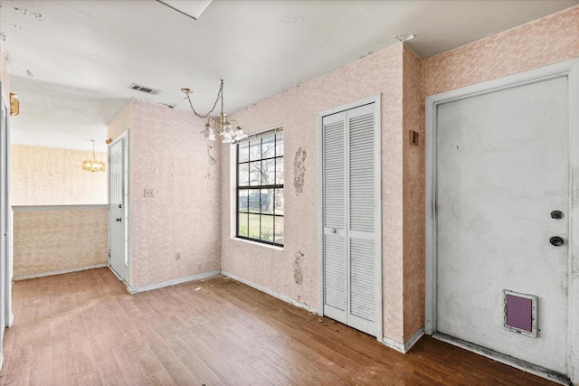 unfurnished dining area with hardwood / wood-style floors and a notable chandelier