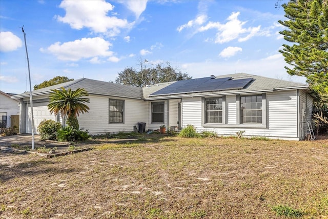 ranch-style home featuring a garage, a front yard, and solar panels