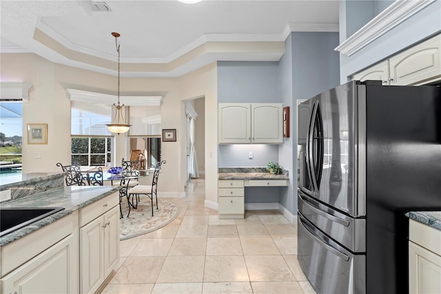 kitchen featuring stainless steel refrigerator with ice dispenser, light stone counters, built in desk, ornamental molding, and a tray ceiling