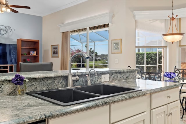 kitchen featuring white cabinetry, light stone countertops, sink, and hanging light fixtures