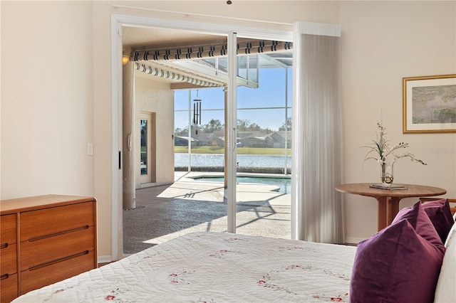 bedroom with a water view, access to exterior, and carpet floors