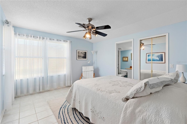 bedroom featuring ceiling fan, light tile patterned floors, and a textured ceiling