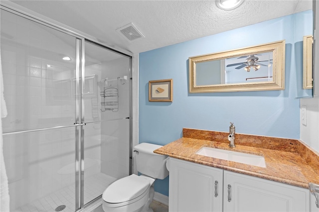 bathroom with toilet, a shower with shower door, a textured ceiling, vanity, and ceiling fan