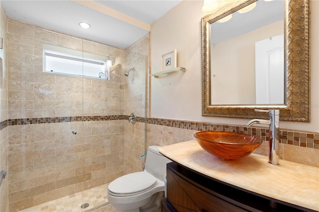 bathroom featuring vanity, tile walls, toilet, and tiled shower