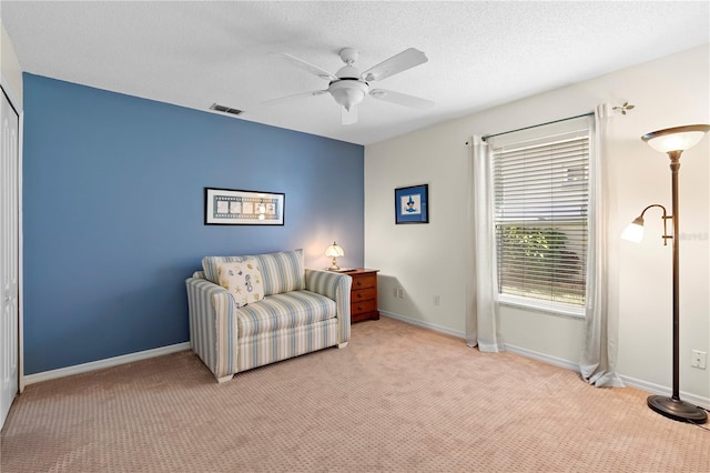 living area with ceiling fan, light carpet, and a textured ceiling