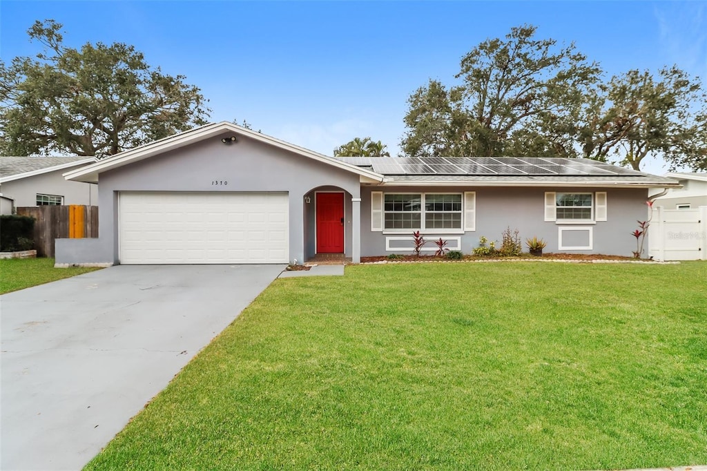 single story home with a garage, a front yard, and solar panels