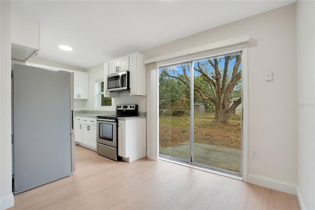 kitchen featuring light stone countertops, light hardwood / wood-style floors, white cabinets, and appliances with stainless steel finishes